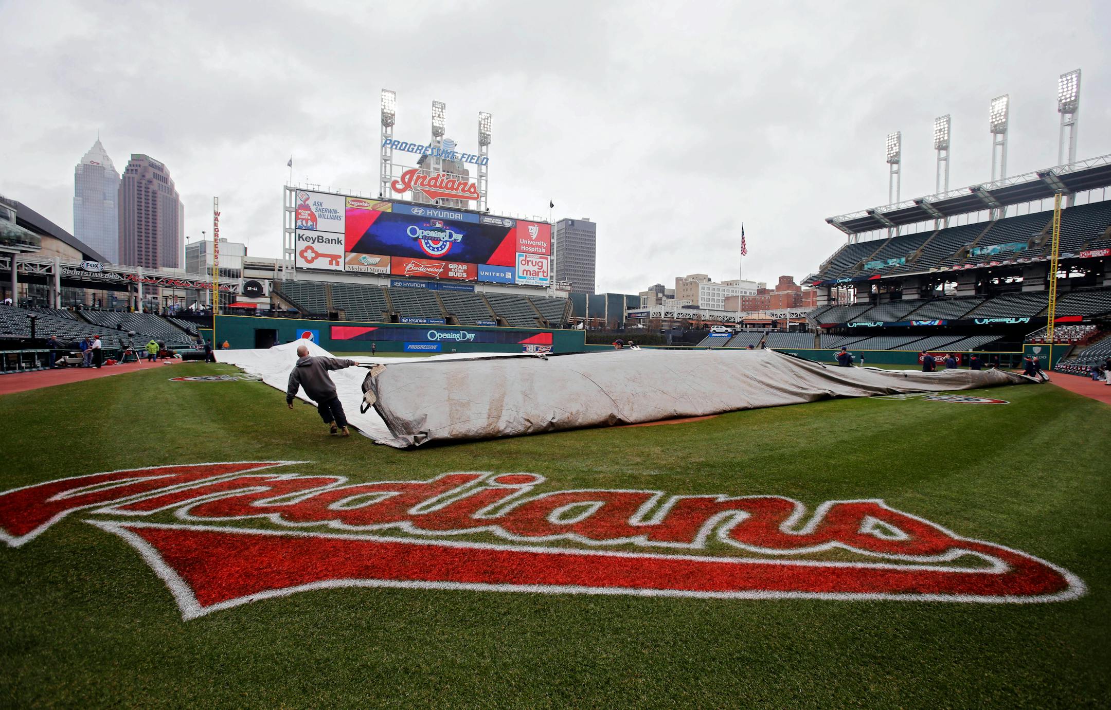 The grounds crew removes the tarp from the infield at Progressive Field before the Cleveland Indians home opener baseball game against the Minnesota Twins Friday, April 4, 2014, in Cleveland. (AP Photo/Mark Duncan)
