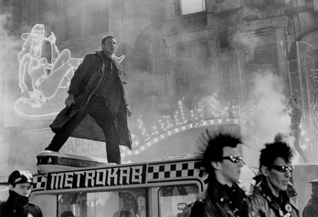 Deckard (Harrison Ford) pursues a suspect through a crowded downtown area of the futuristic city in Blade Runner.