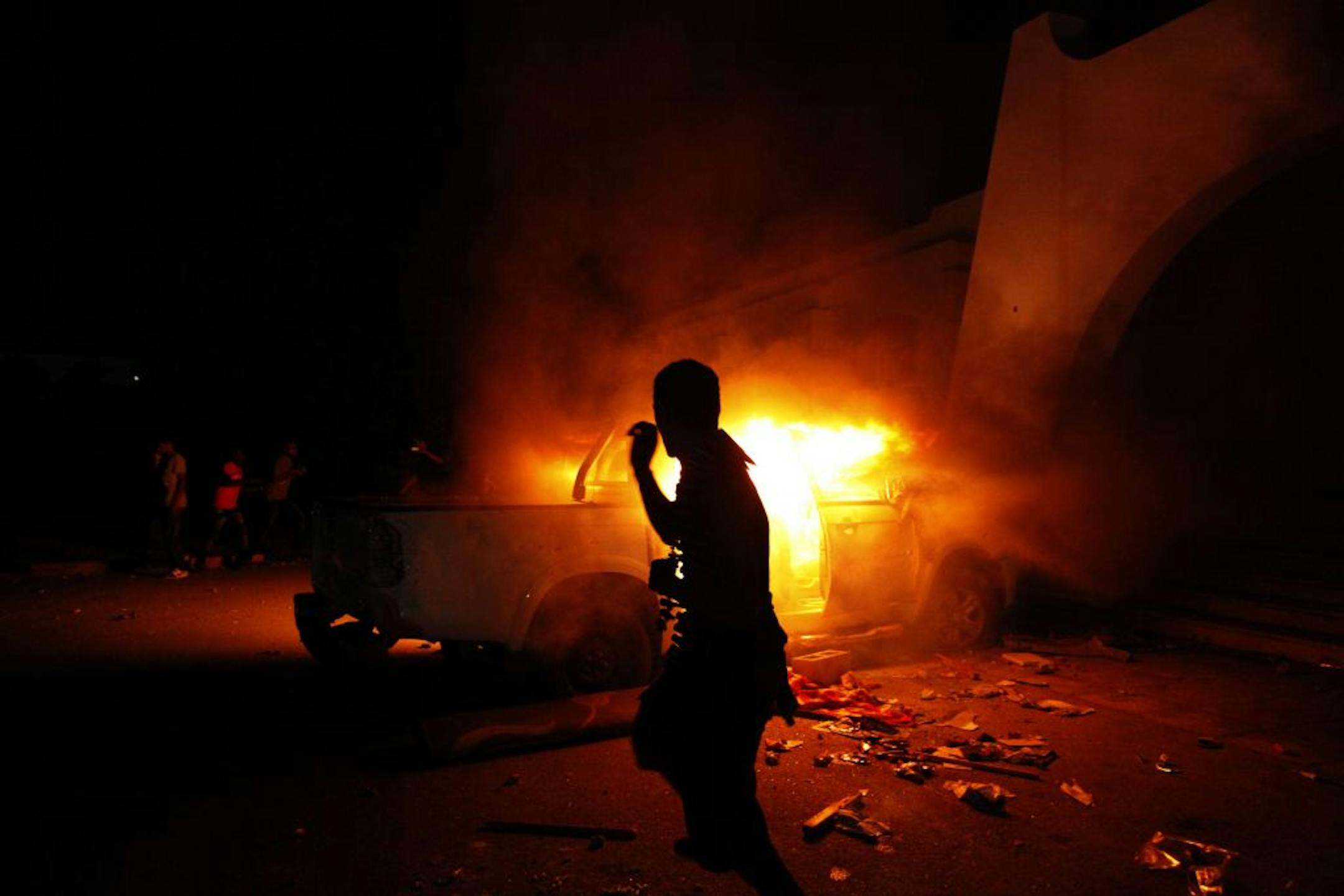 A Libyan civilian watches one of Ansar al-Shariah Brigades cars on fire, after hundreds of Libyans, Libyan Military, and Police raided the Brigades base, in Benghazi, Libya, Friday, Sept. 21, 2012.