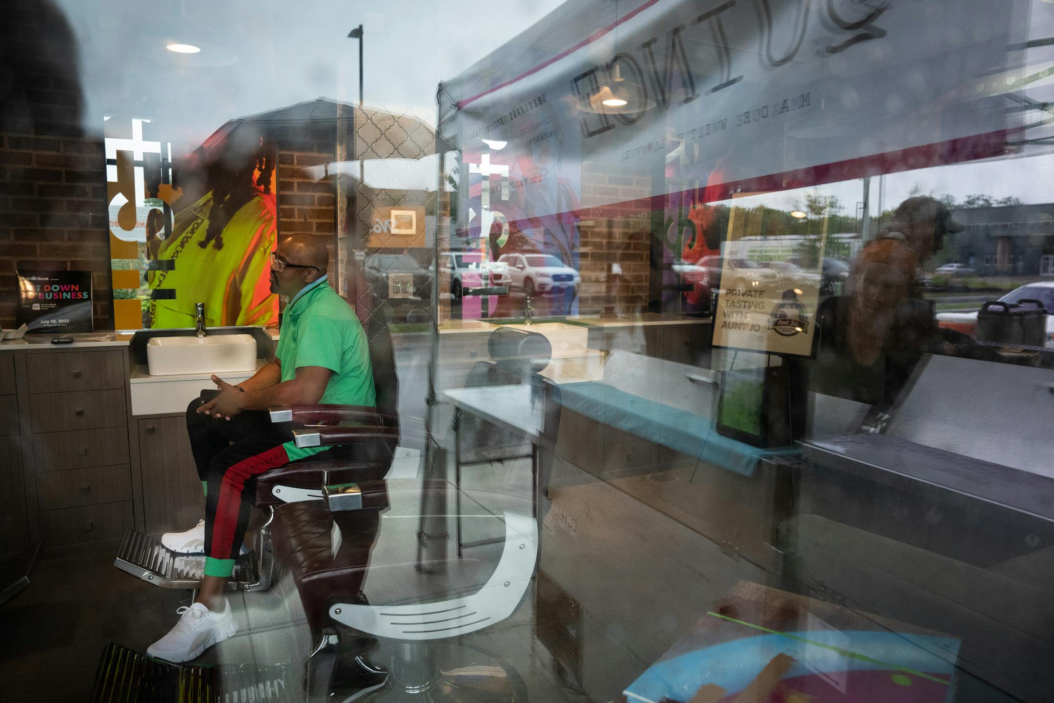 Houston White had a meeting in his future barber shop while people, reflected in the window, lined up in the rain outside to order burrito's from Quinche outside the store.