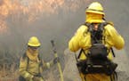 Firefighters Ryan Foley, center, and Andrew Arthen with San Bernardino Cal Fire make a stand in front of an advancing wildfire as they protect a home 