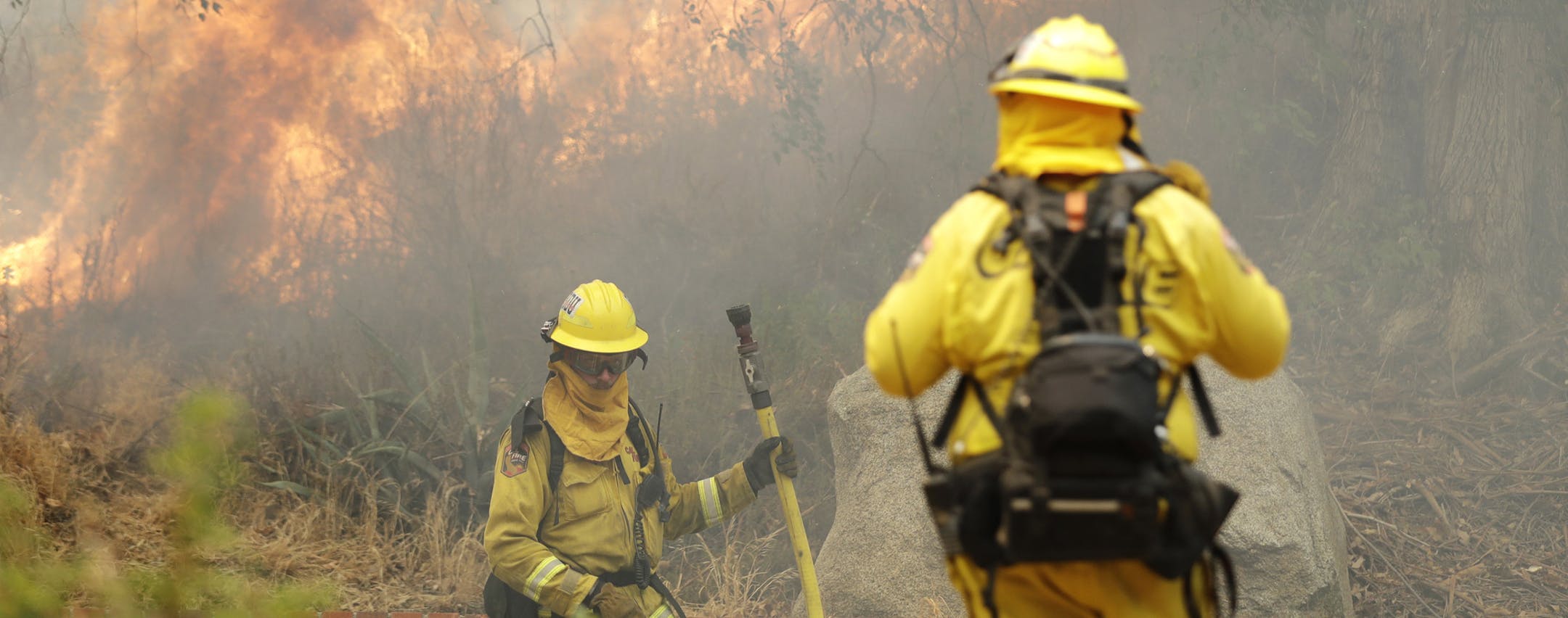 Firefighters Ryan Foley, center, and Andrew Arthen with San Bernardino Cal Fire make a stand in front of an advancing wildfire as they protect a home Friday, Aug. 10, 2018, in Lake Elsinore, Calif. Firefighters on Friday are protecting foothill neighborhoods in the city of Lake Elsinore near where the blaze flared up amid unpredictable winds a day earlier. (AP Photo/Marcio Jose Sanchez)