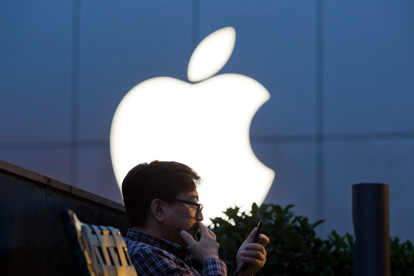 FILE - In this Friday, May 13, 2016, file photo, a man uses his mobile phone near an Apple store in Beijing. On Wednesday, July 12, 2017, Apple announced it will open a data center in mainland China with ties to the country's government, raising concerns about the security of iCloud accounts that store personal information transferred from iPhones, iPads and Mac computers there. (AP Photo/Ng Han Guan, File)