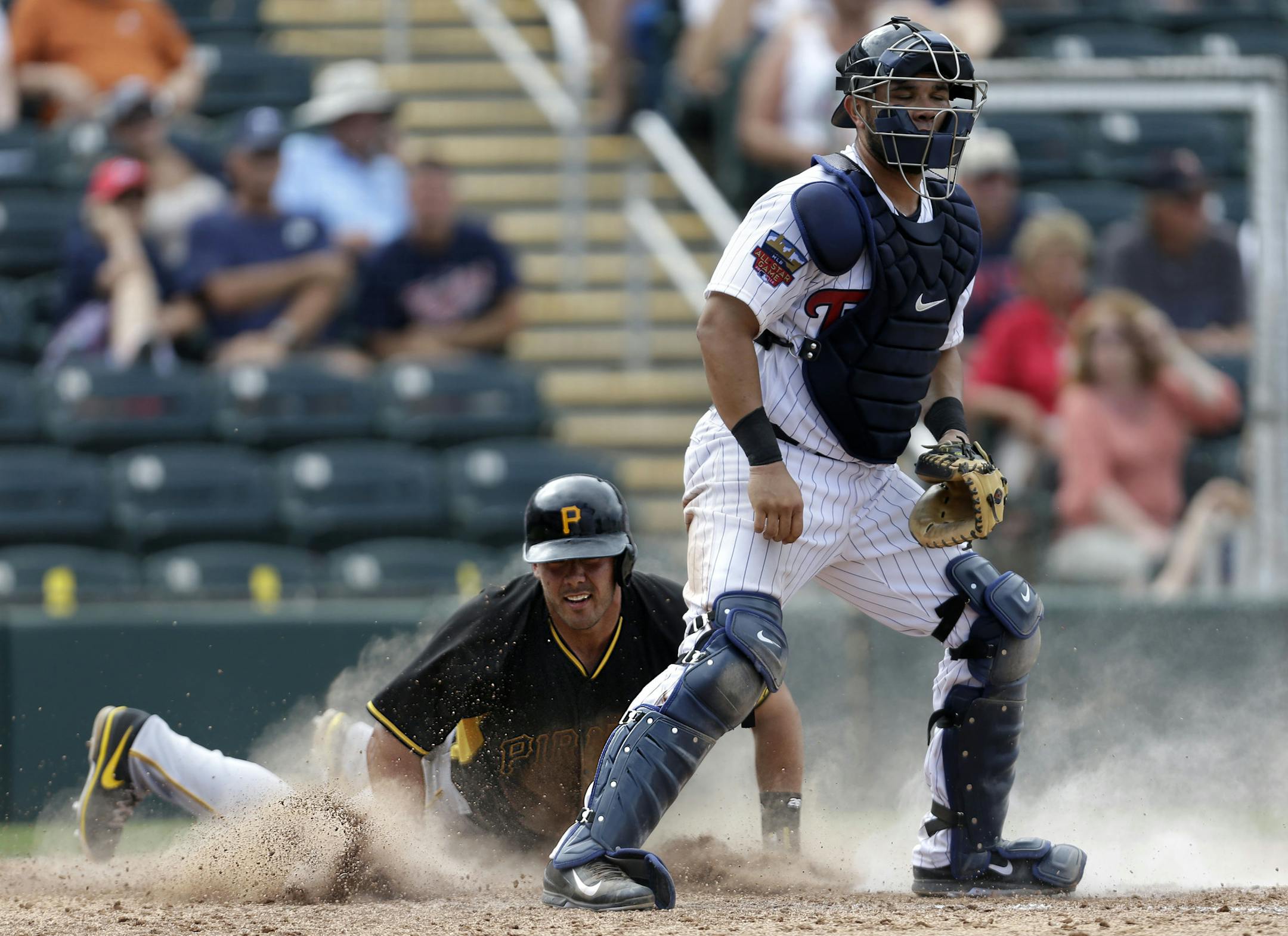 Pittsburgh Pirates Tony Sanchez reaches home on an RBI single by Chase d'Arnaud as Minnesota Twins catcher Josmil Pinto covers in the 8th inning of an exhibition baseball game in Fort Myers, Fla., Wednesday, March 12, 2014. The Pirates won 8-4. (AP Photo/Gerald Herbert)