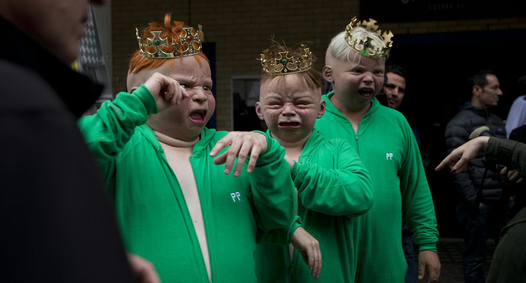 Representatives from a betting company wear baby masks as they perform a publicity stunt outside St. Mary's Hospital in London, Friday, July 12, 2013. Media are preparing for royal-mania as Britain's Kate, Duchess of Cambridge is expected to give birth to the new third-in-line to the throne in mid-July, at the Lindo Wing. Cameras from all over the world are set to be jostling outside for an exclusive first glimpse of Britain's Prince William and the Duchess of Cambridge's first child. (AP Photo/