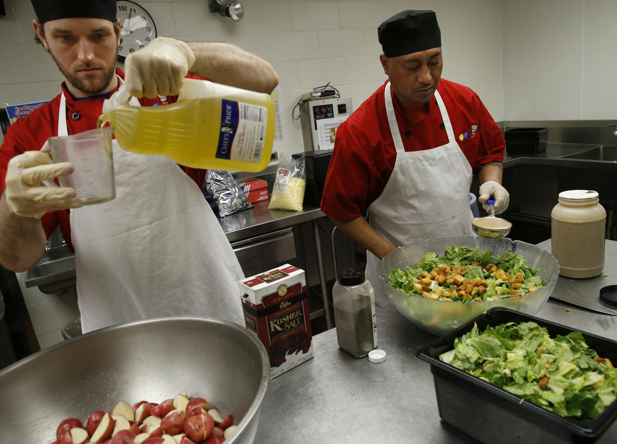 At the cafeteria of Washburn H.S., Brody Hills mixes some fresh cut red potatoes with salt, pepper, and an olive oil mix as Leatuvai Tulimasealii(cq) makes a caesar sald. This is all part of new approach of fresh and local ingredients on the student menu.]rtsong-taatarii@startribune.com