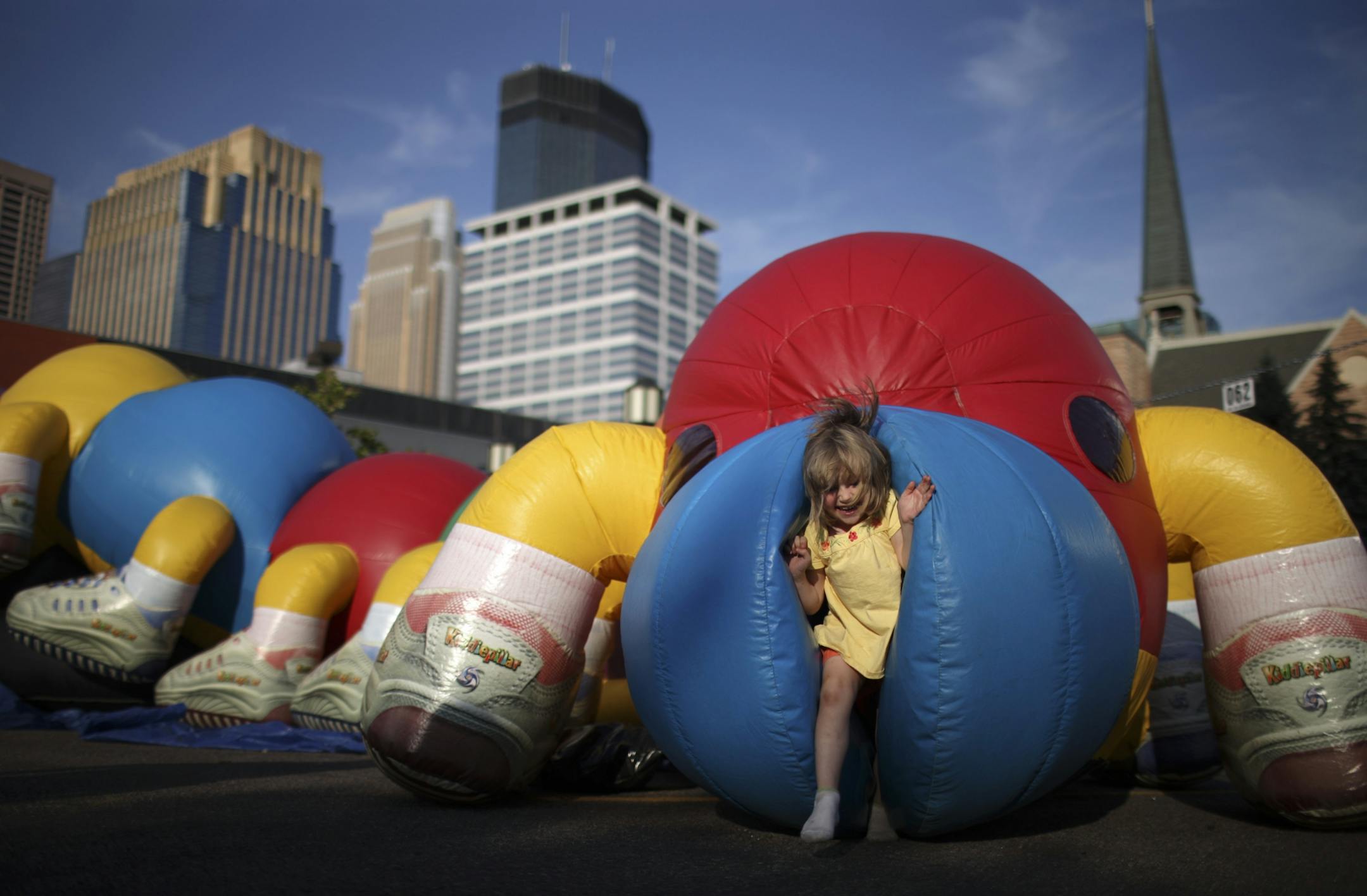 July 22, 2009: A child emerged from a giant blow-up caterpillar set up in the parking lot of First Baptist Church on Hennepin Ave. before the Aquatennial torchlight parade.