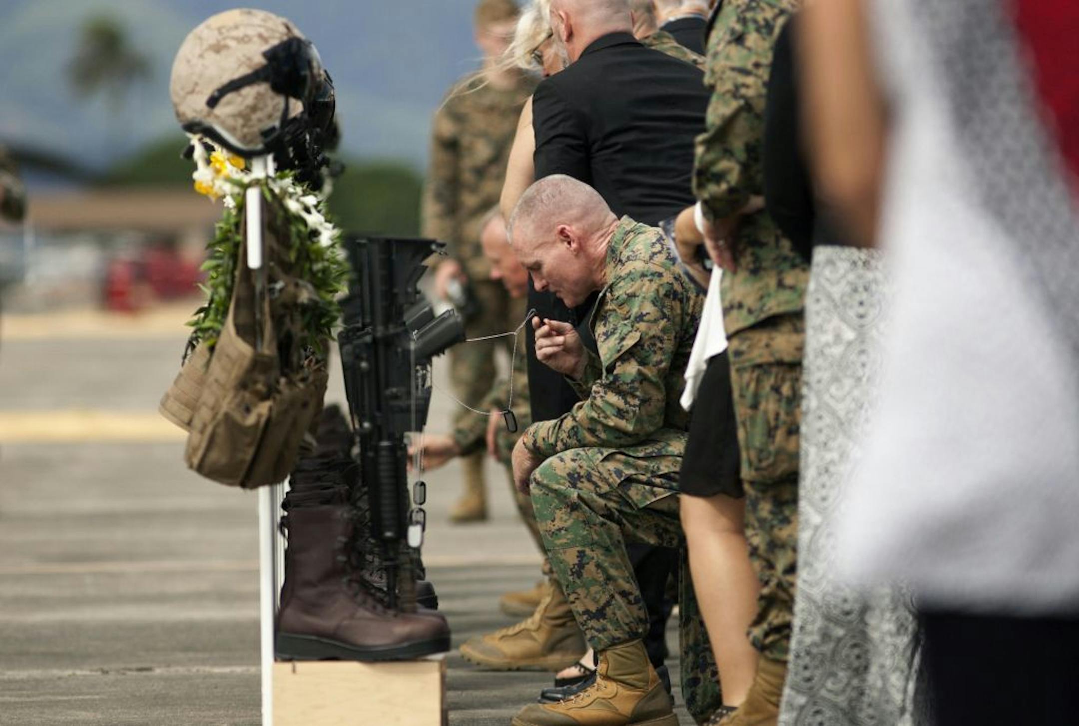 Family, friends and comrads pay their respects during a memorial service for the 12 U.S. Marines who died when their helicopters crashed off the North Shore of Oahu, Hawaii, Friday, Jan. 22, 2016, at Marine Corps Base Hawaii. Servicemen draped flight gear on 12 white crosses Friday to commemorate the Marines who died when two helicopters crashed off the coast of Hawaii during a nighttime training mission. Military members and families gathered for the memorial service at Marine Corps Base Hawaii