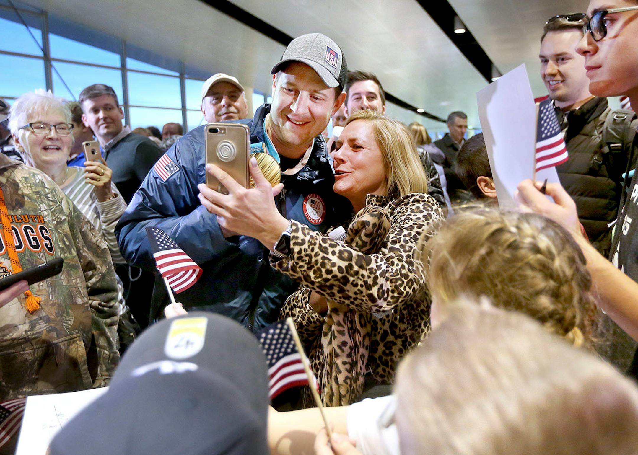 Nancy Litman of Duluth, a friend of John Shuster, uses her phone to take a selfie during the homecoming of the Duluth curling team at the Duluth International Airport Monday evening. Bob King / rking@duluthnews.com