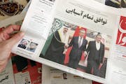 A man in Tehran holds a local newspaper reporting on its front page the China-brokered deal between Iran and Saudi Arabia to restore ties, signed in B