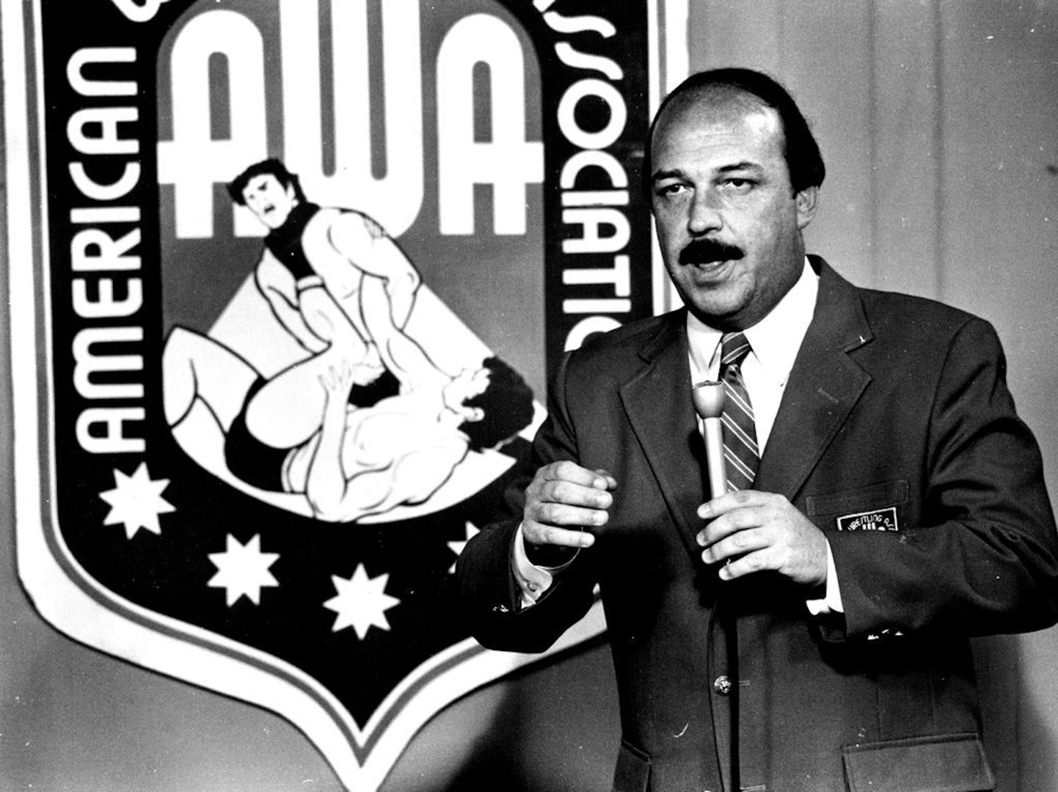 Gene Okerlund in 1982 with his microphone, his red blazer and familiar American Wrestling Association seal. Okerlund, who first made his name as a pro wrestling announcer with Minnesota's AWA, has died at age 76, World Wresting Entertainment announced Wednesday.