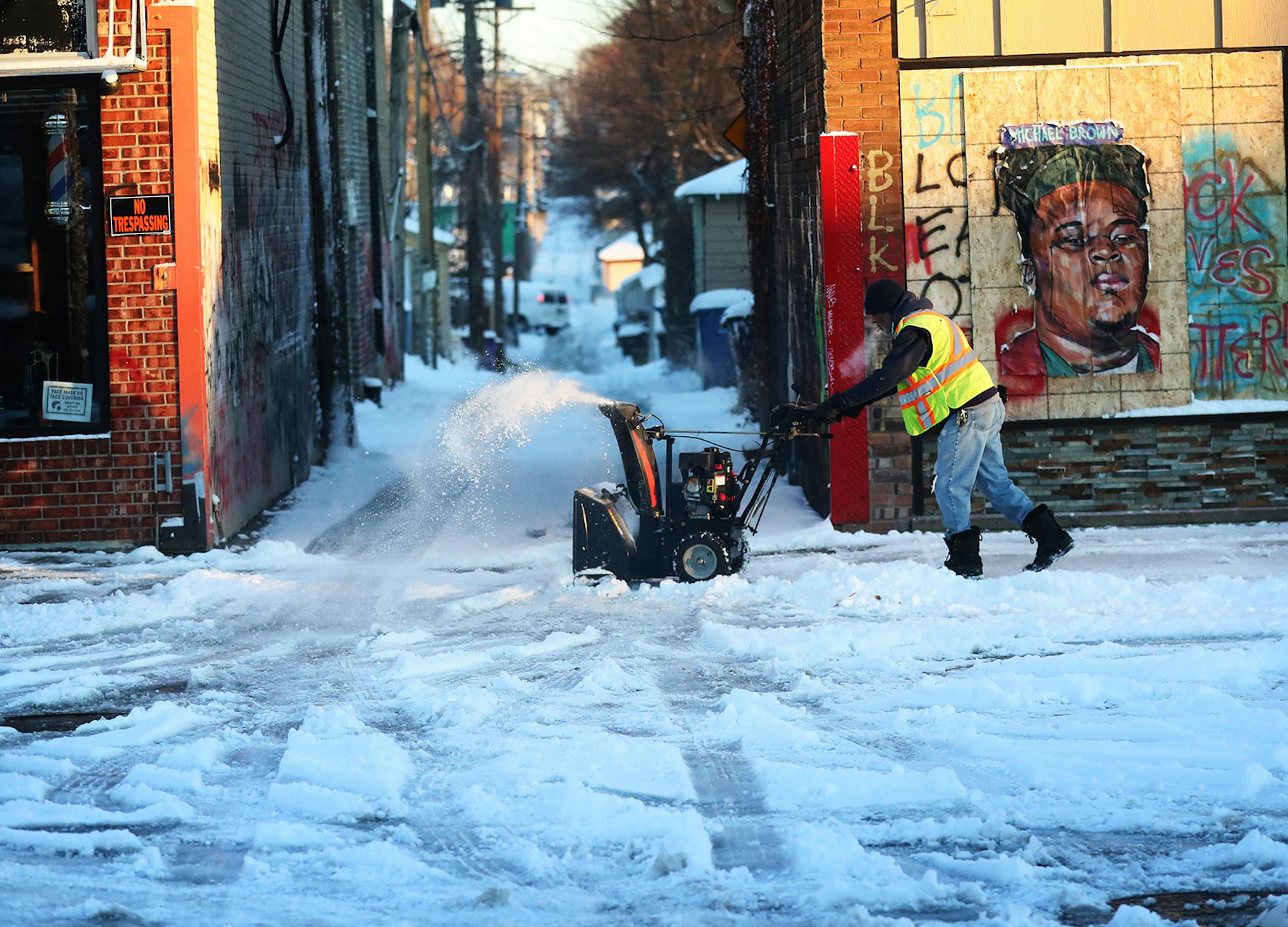 A man blows fresh snow near an alley behind George Floyd Square at 38th and Chicago Ave. S. Wednesday in Minneapolis.