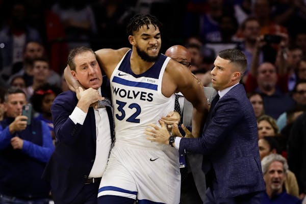 Minnesota Timberwolves' Karl-Anthony Towns is led away after an altercation with Philadelphia 76ers' Joel Embiid during the second half of an NBA bask