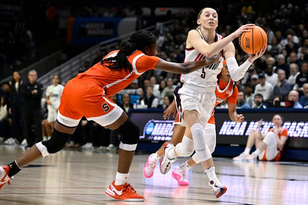 UConn guard Paige Bueckers, right, looks to pass while guarded by Syracuse forward Alyssa Latham in the first half of a second-round game in the NCAA 