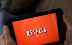 FILE - In this Friday, Jan. 17, 2014, file photo, a person displays Netflix on a tablet in North Andover, Mass. Netflix subscribers can now download s