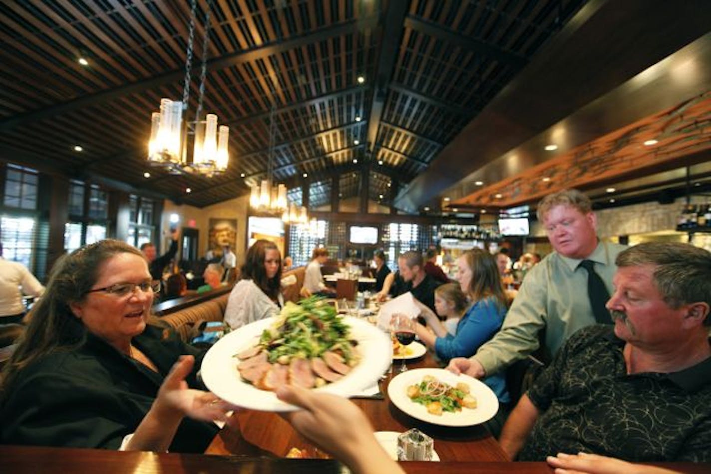 Manager Erik Gladden delivers appetizers to Anne Trost, left, and Ed Trost, right, during a busy night at Porter Creek Hardwood Grill in Burnsville.