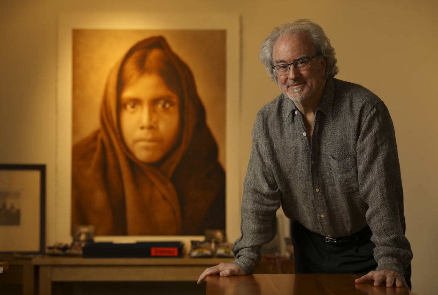 Christopher Cardozo in his Minneapolis office near a large print of the Edward S. Curtis portrait "Qahatika Girl, 1907."