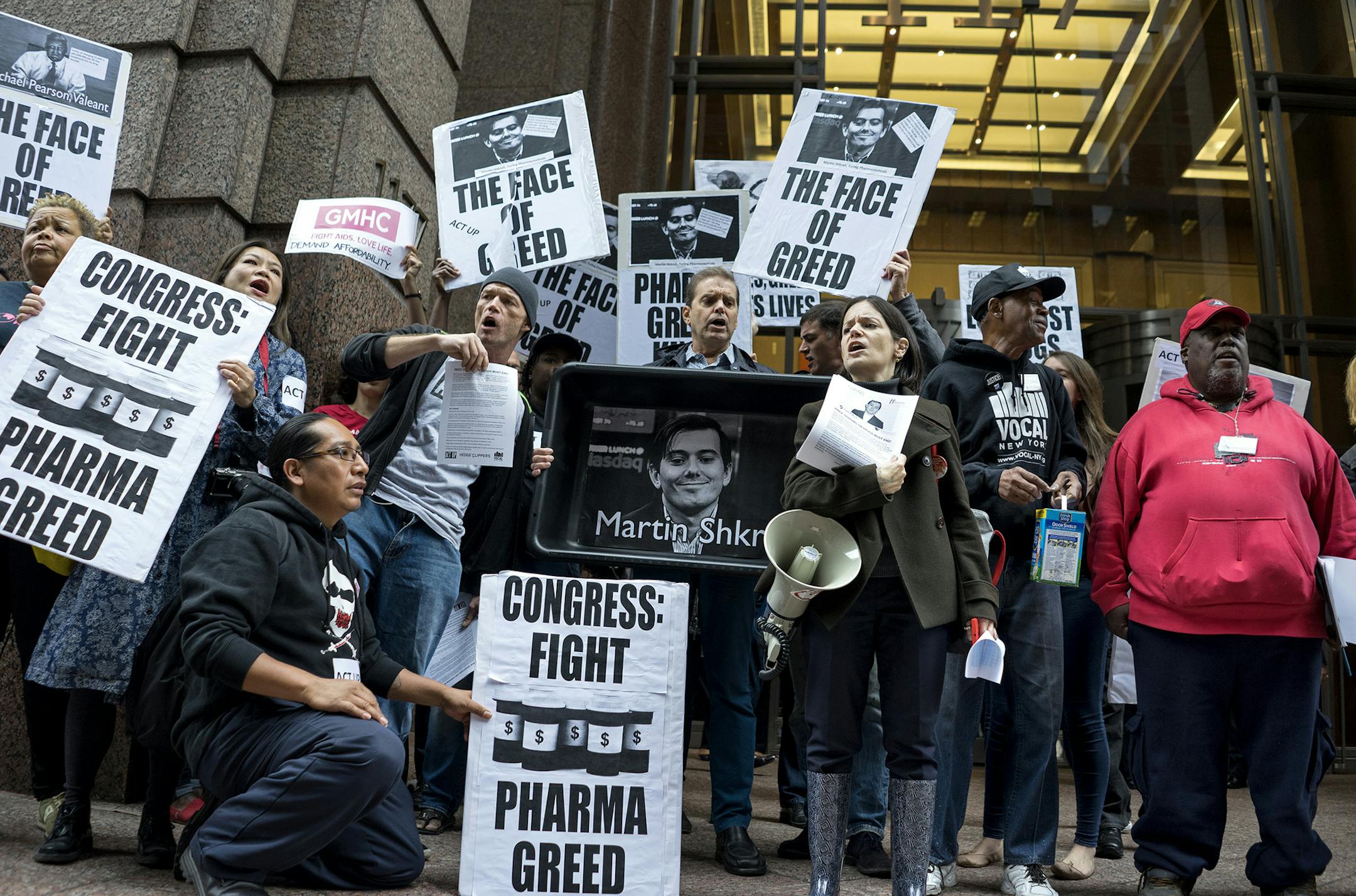 Activists hold signs containing the image of Turing Pharmaceuticals CEO Martin Shkreli in front the building that houses Turing's offices, in New York, Thursday, Oct. 1, 2015, during a protest highlighting pharmaceutical drug pricing.