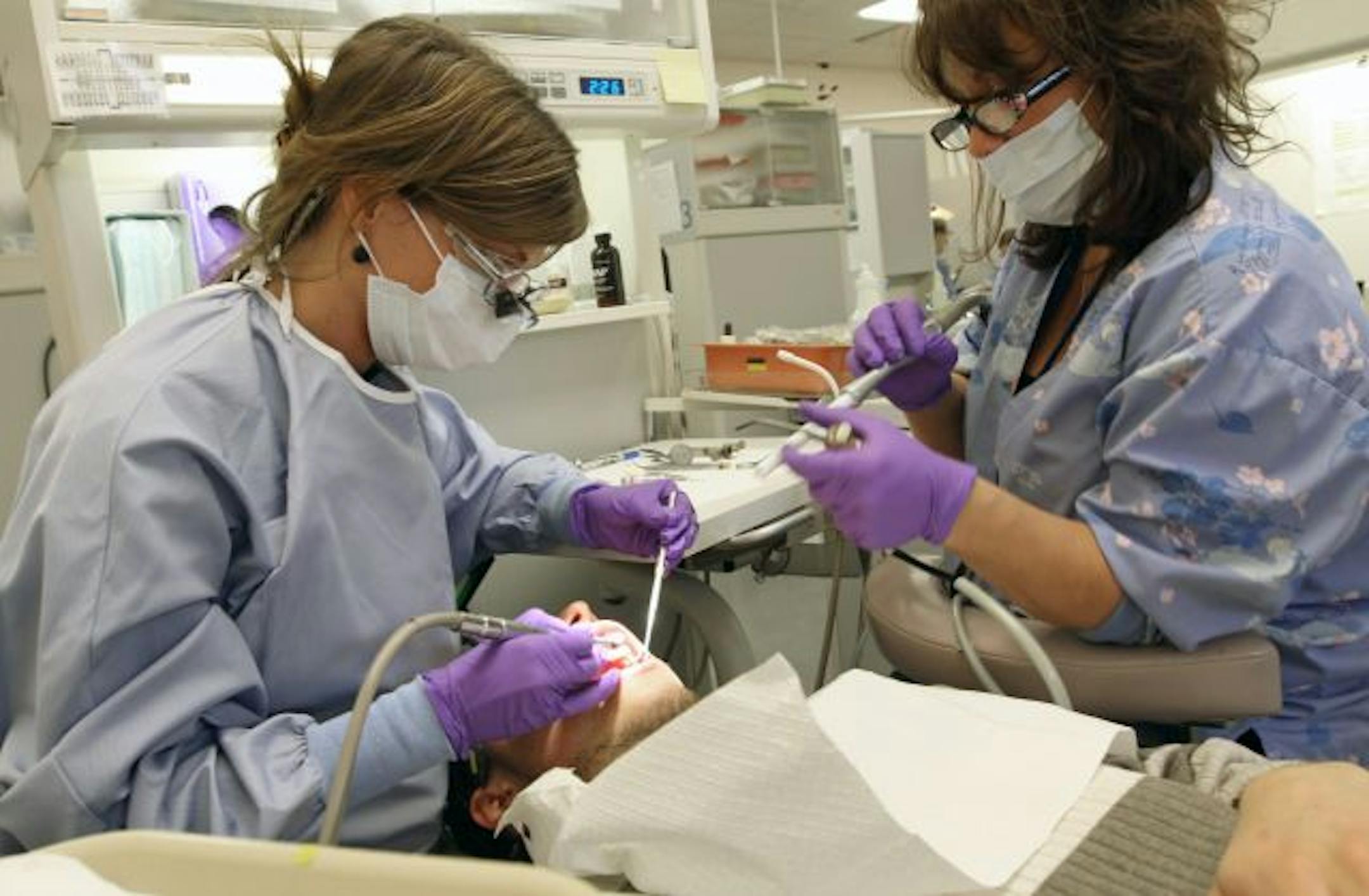 Dr. Michelle Olson, left, and dental assistant Kim Watson worked on an uninsured patient from St. Paul at the Community-University Health Care Center in south Minneapolis.