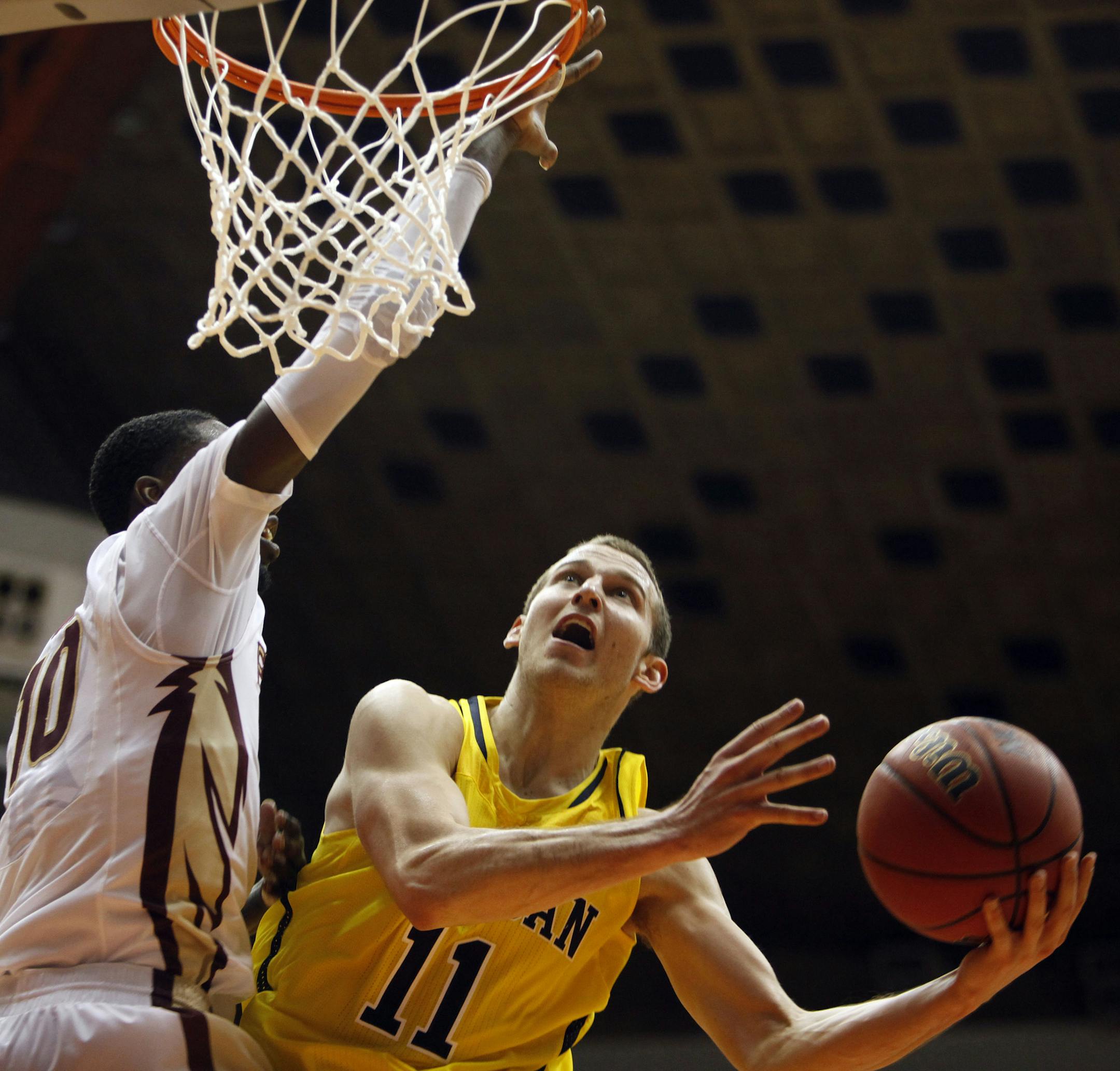 Michigan guard Nik Stauskas, right, goes to the basket against Florida State forward Okaro White during a NCAA college basketball game in San Juan, Puerto Rico, Friday, Nov. 22, 2013. (AP Photo/Ricardo Arduengo)