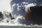 In this photo provided by Shane Turpin, a "firehose" lava stream from Kilauea Volcano shoots out from a sea cliff on Hawaii's Big Island, Wednesday, F