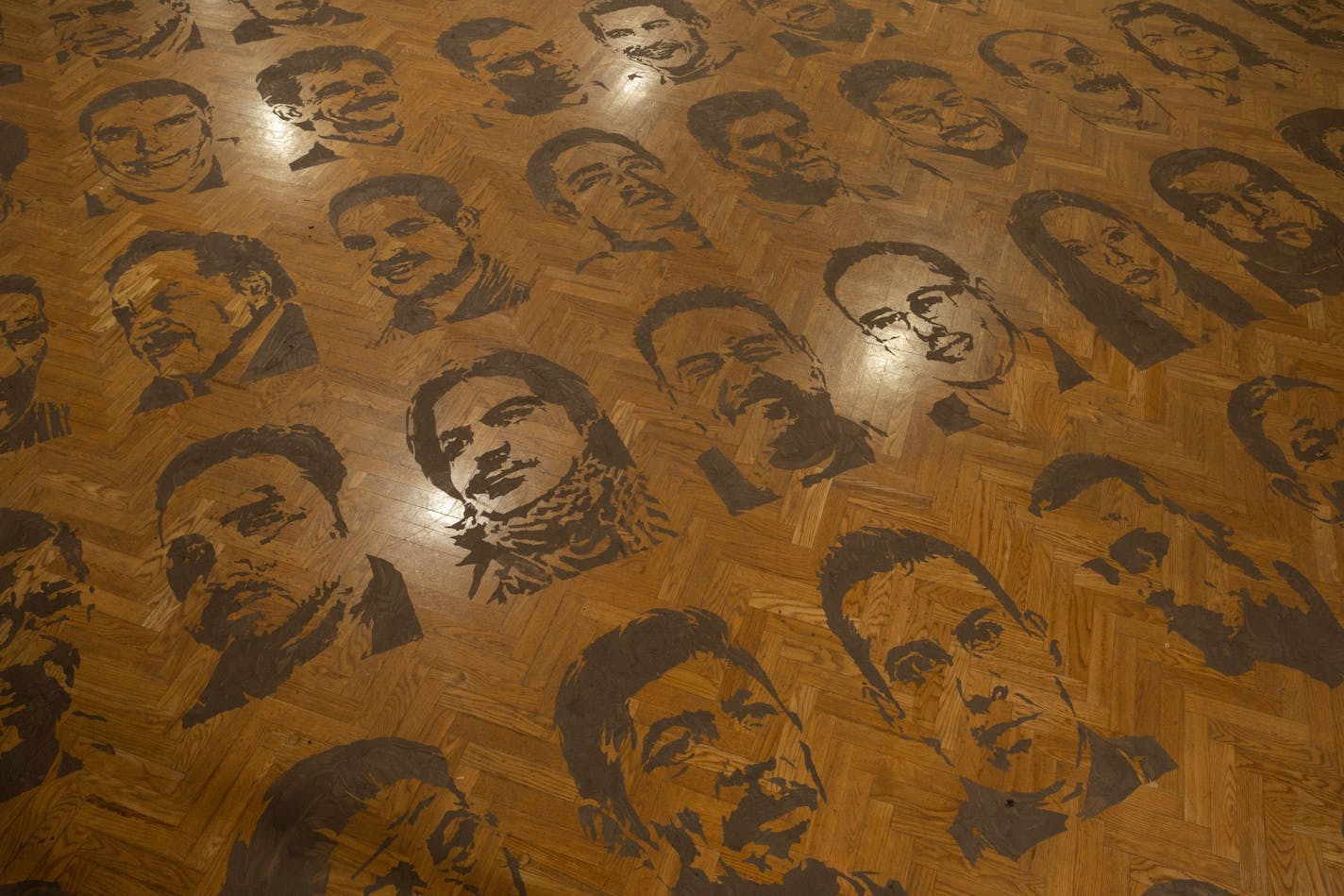 Faces of killed or missing Mexican journalists, stenciled onto a gallery floor of Mia by artist Jonathan Herrera Soto.