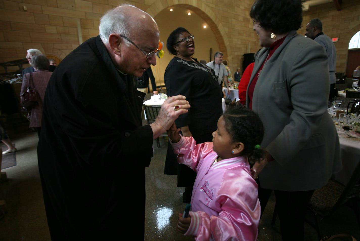 Archbishop Harry Flynn high-fived Alyssa Downwind, 4, after he spoke Friday at the luncheon meeting of the St. Paul Council of Churches.