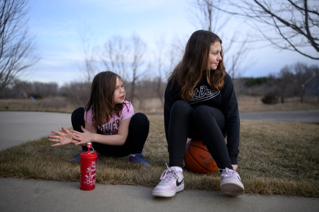 Zoey Voigt, left, 10, and sister Abigail, 11, look to the neighbor kids across the street Wednesday in St. Augusta.