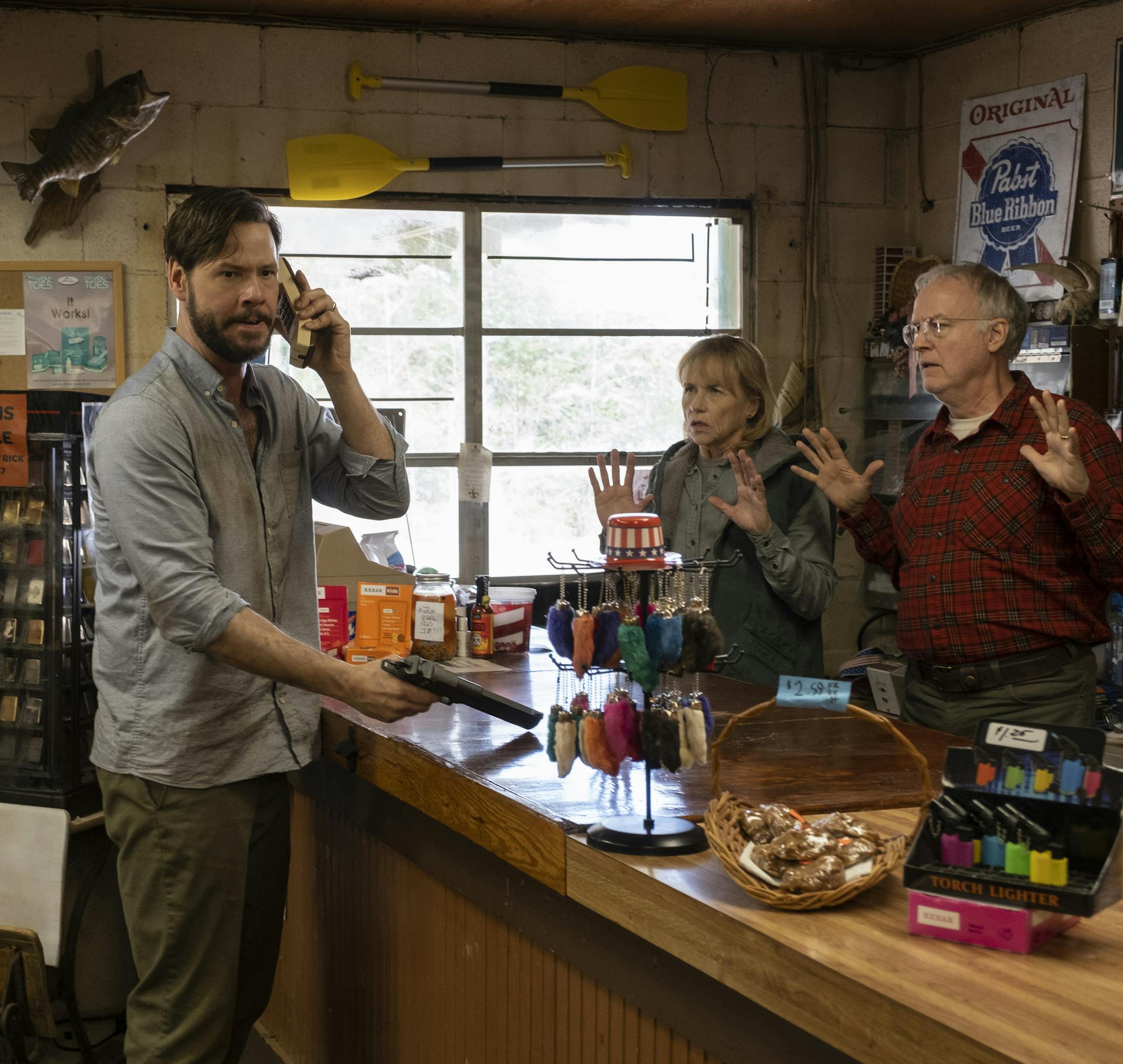 (from left) Members of the hunted (Kate Nowlin, back to camera, Ike Barinholtz), seek help from the owners of a gas station (Amy Madigan, Reed Birney) in The Hunt, directed by Craig Zobel.