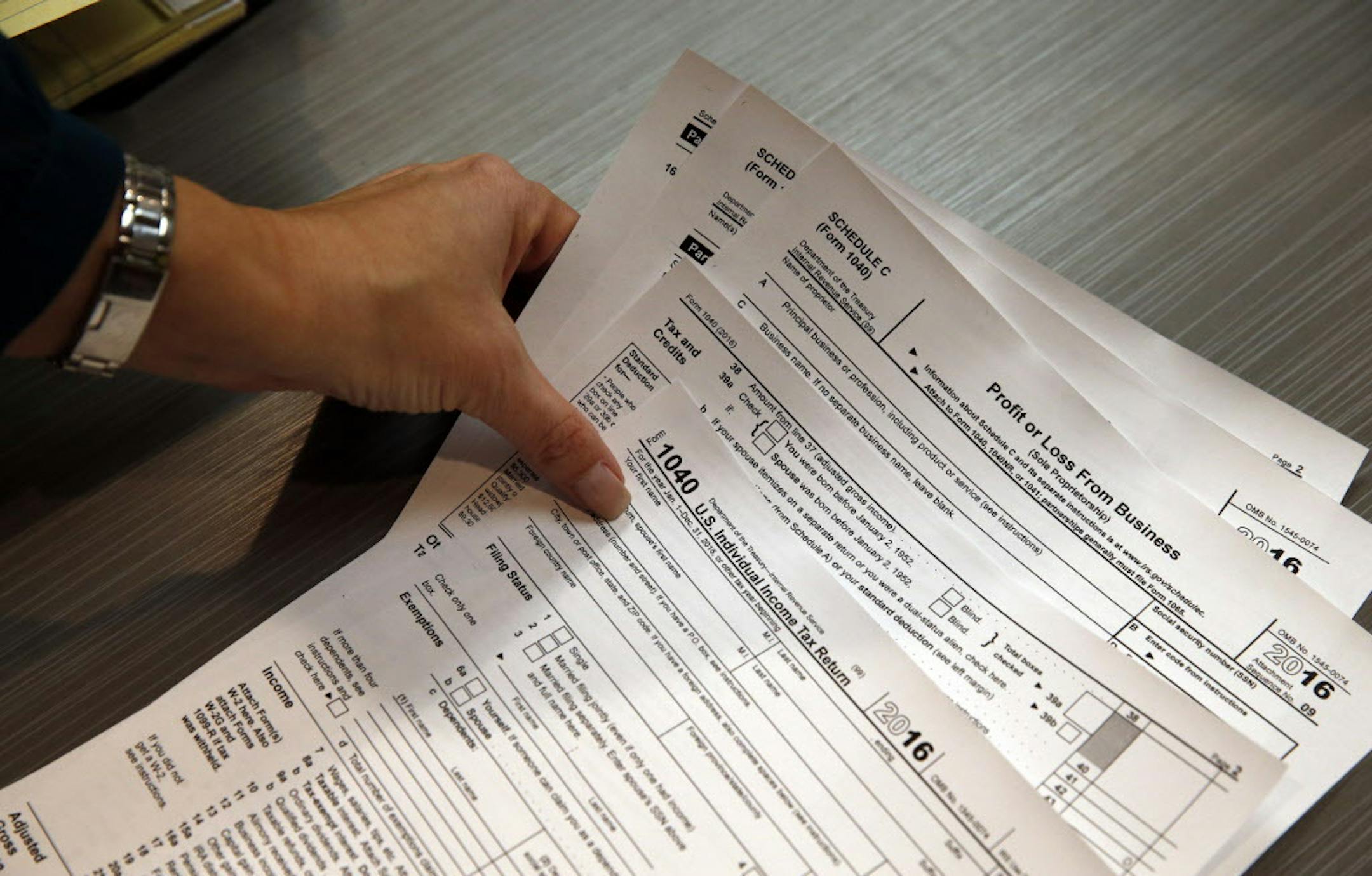 FILE - In this Jan. 14, 2017 file photo, tax professional and tax preparation firm owner Alicia Utley reaches for hard copies of tax forms while working to stay caught up at the start of the tax season rush in her offices at Infinite Tax Solutions, in Boulder, Colo. Millions of working Americans should start seeing fatter paychecks as early as next month, the IRS says, as a result of the recently passed tax law. (AP Photo/Brennan Linsley)