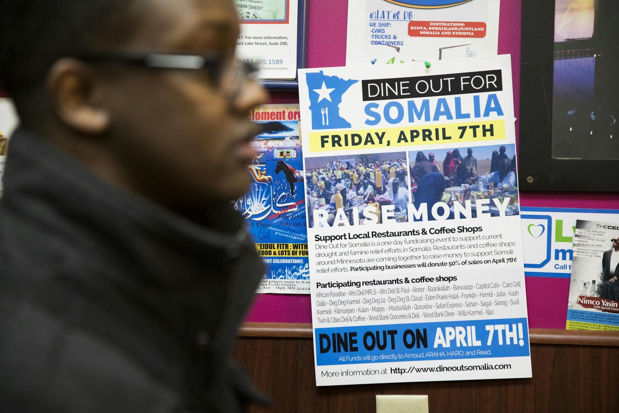 Khalid Mohamed gets a phone business to hang a sign for Dine Out for Somalia while at Village Market.