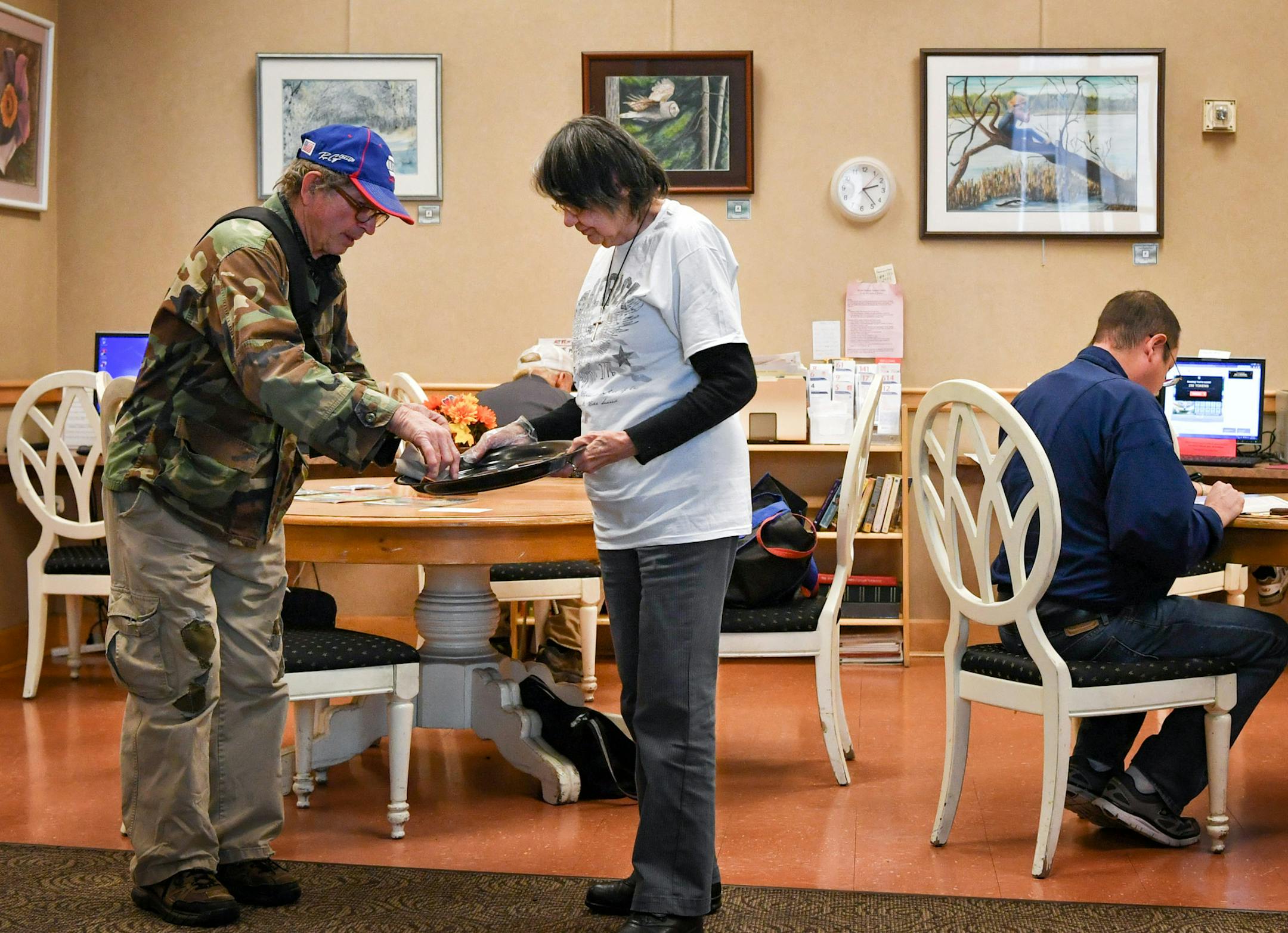 Skyway Senior Center volunteer Willie Carignan, center, served cookies to some of the seniors there. The paintings on the wall are by the center&#x2019;s Artist of the Month Howard Carson.