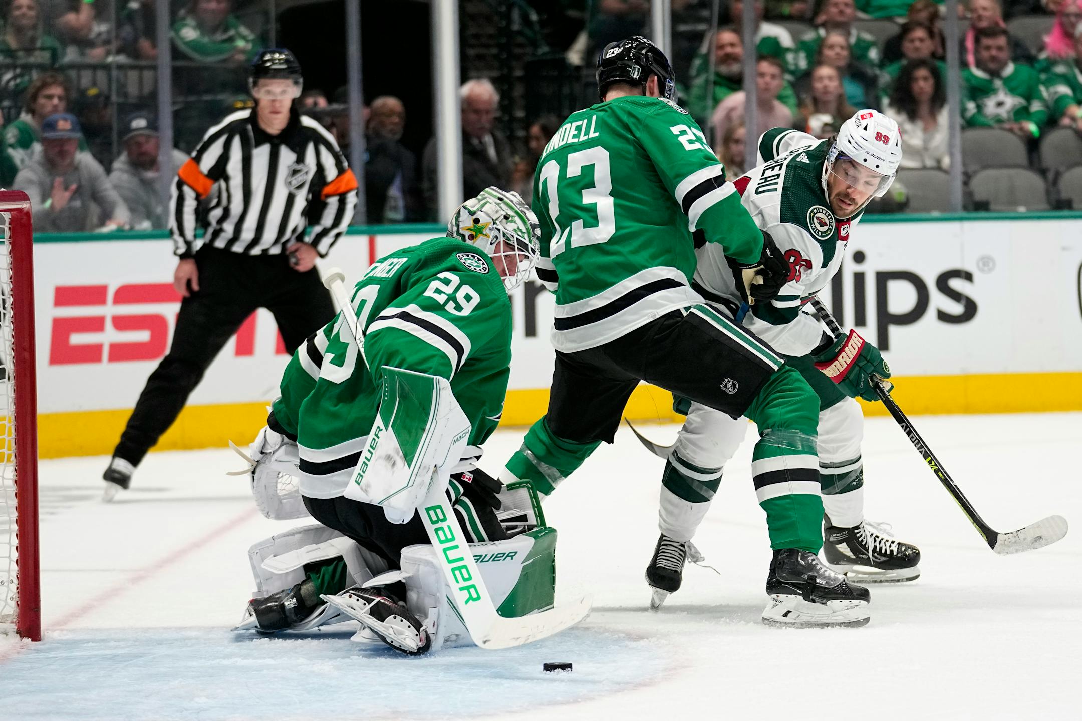 Dallas Stars goaltender Jake Oettinger (29) moves to secure the puck as Esa Lindell (23) helps against pressure from Minnesota Wild center Frederick Gaudreau (89) in the second period of Game 1.