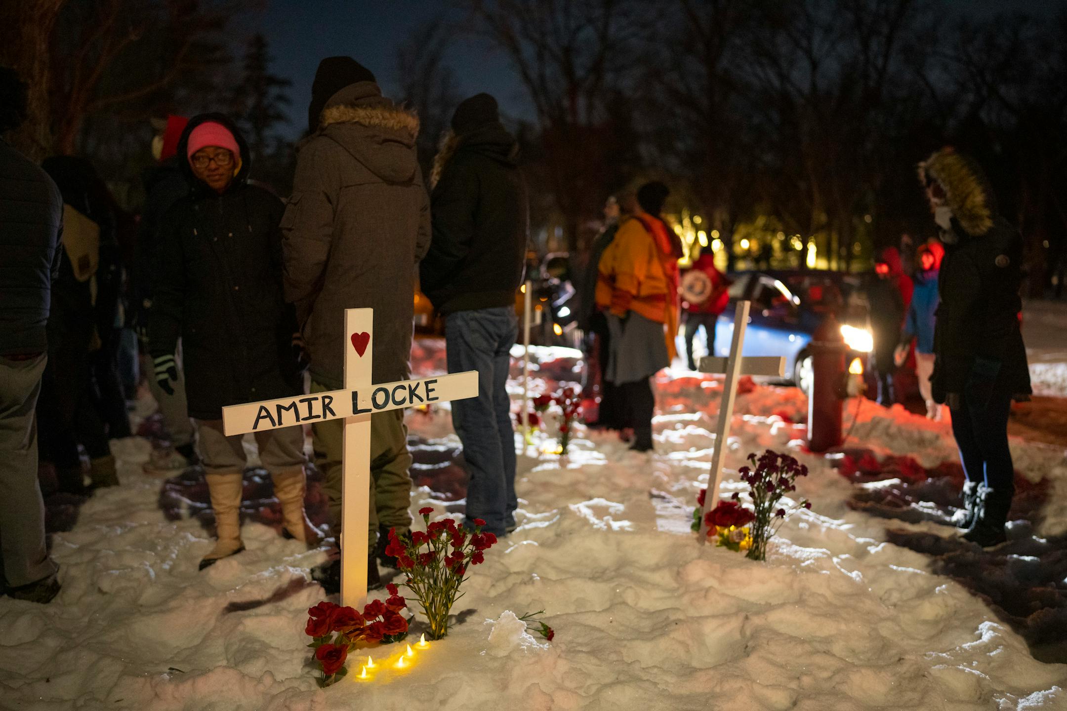 Demonstrators stood among crosses planted in the boulevard as they listened to speakers outside homes in the Cedar-Isles-Dean on Sunday night, February 6, 2022 in Minneapolis.