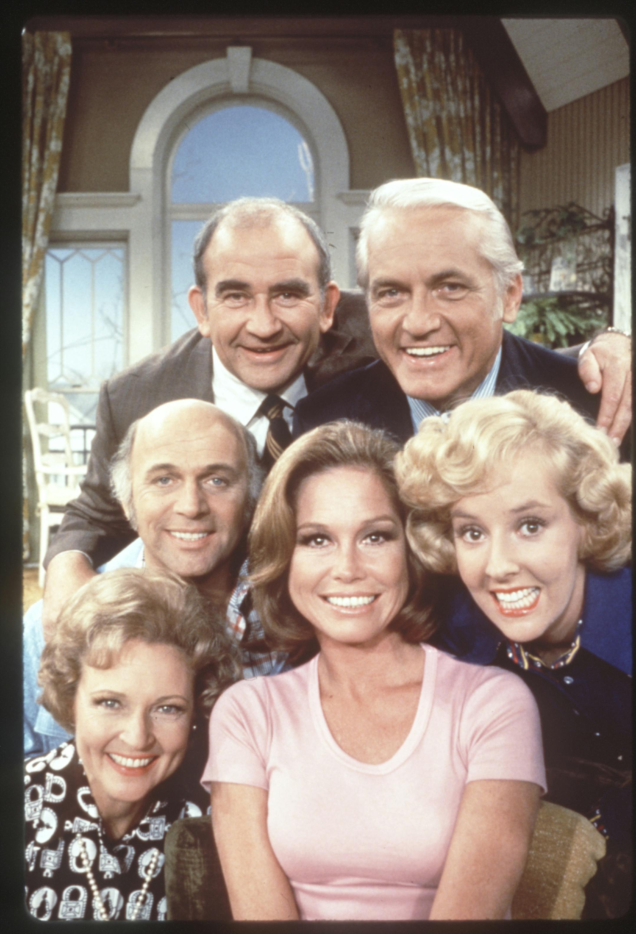 The Mary Tyler Moore Show (television). Mary Tyler Moore is front and center. Ed Asner and Ted Knight are left to right in back. Georgia Engel is at right. Gavin MacLeod is at left in front of Asner. Betty White is at lower left. File photo courtesy of CBS Television.