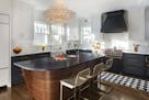 Stephanie Shimp's black-and-white chef's kitchen — with a pop of hot pink in the Blue Star range knobs — features a crystal chandelier over a thre