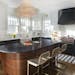 Stephanie Shimp's black-and-white chef's kitchen — with a pop of hot pink in the Blue Star range knobs — features a crystal chandelier over a thre