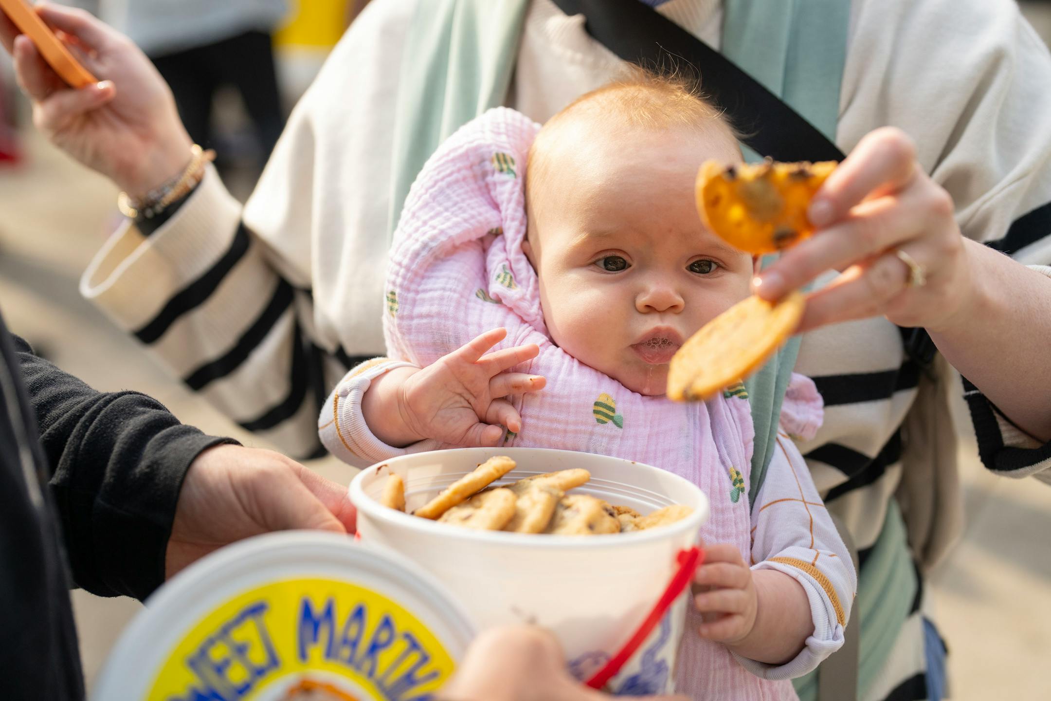 Louise Siemers, 6 months, watches as her mother, Chelsea, pulls Sweet Martha’s Cookie Jar cookies out of a bucket on opening morning of the Minnesota State Fair at The State Fairgrounds in Falcon Heights on Aug. 22, 2024.