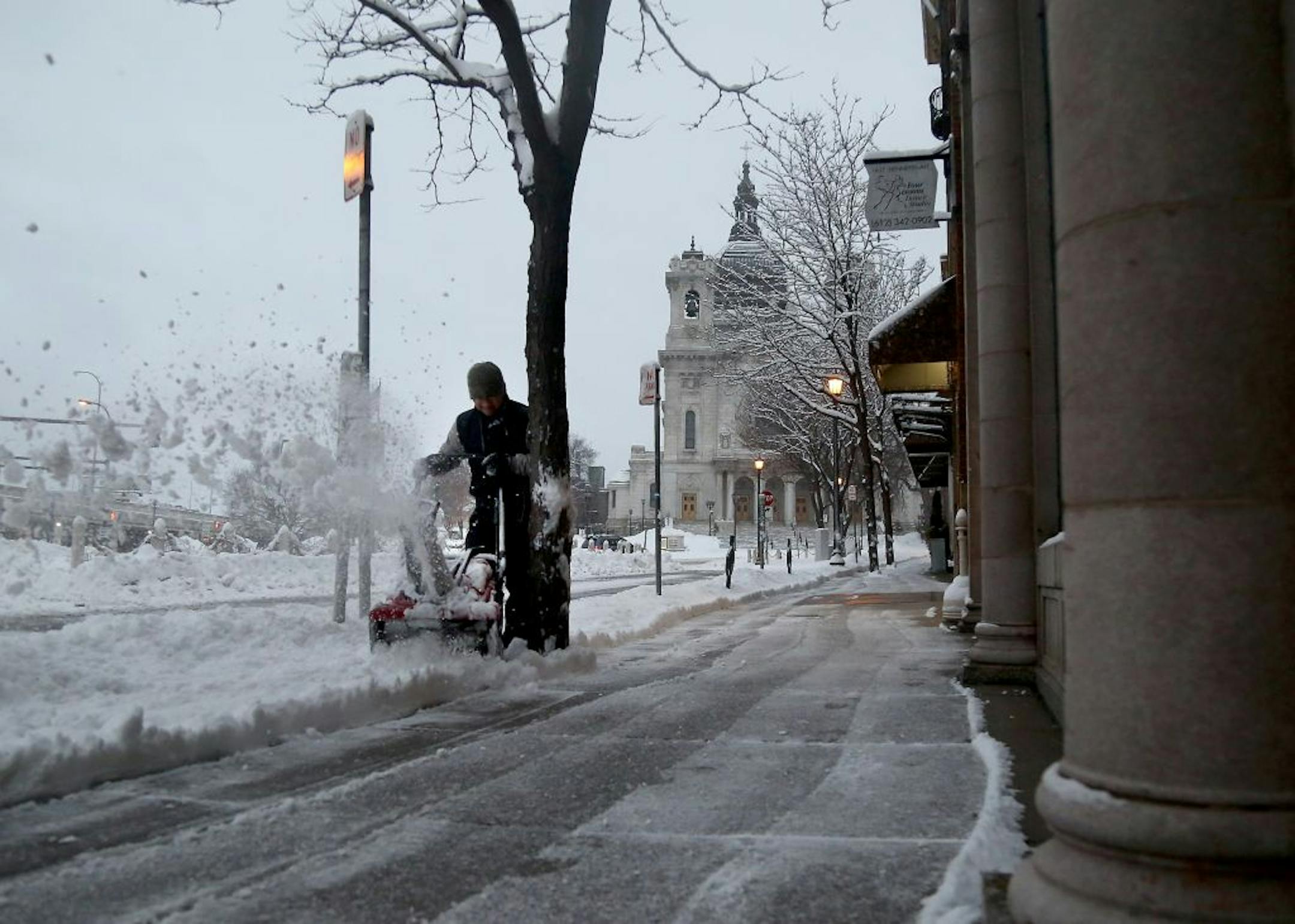Maintenance worker Manny Lema pushes through fresh snowfall Tuesday morning early near Loring Park.