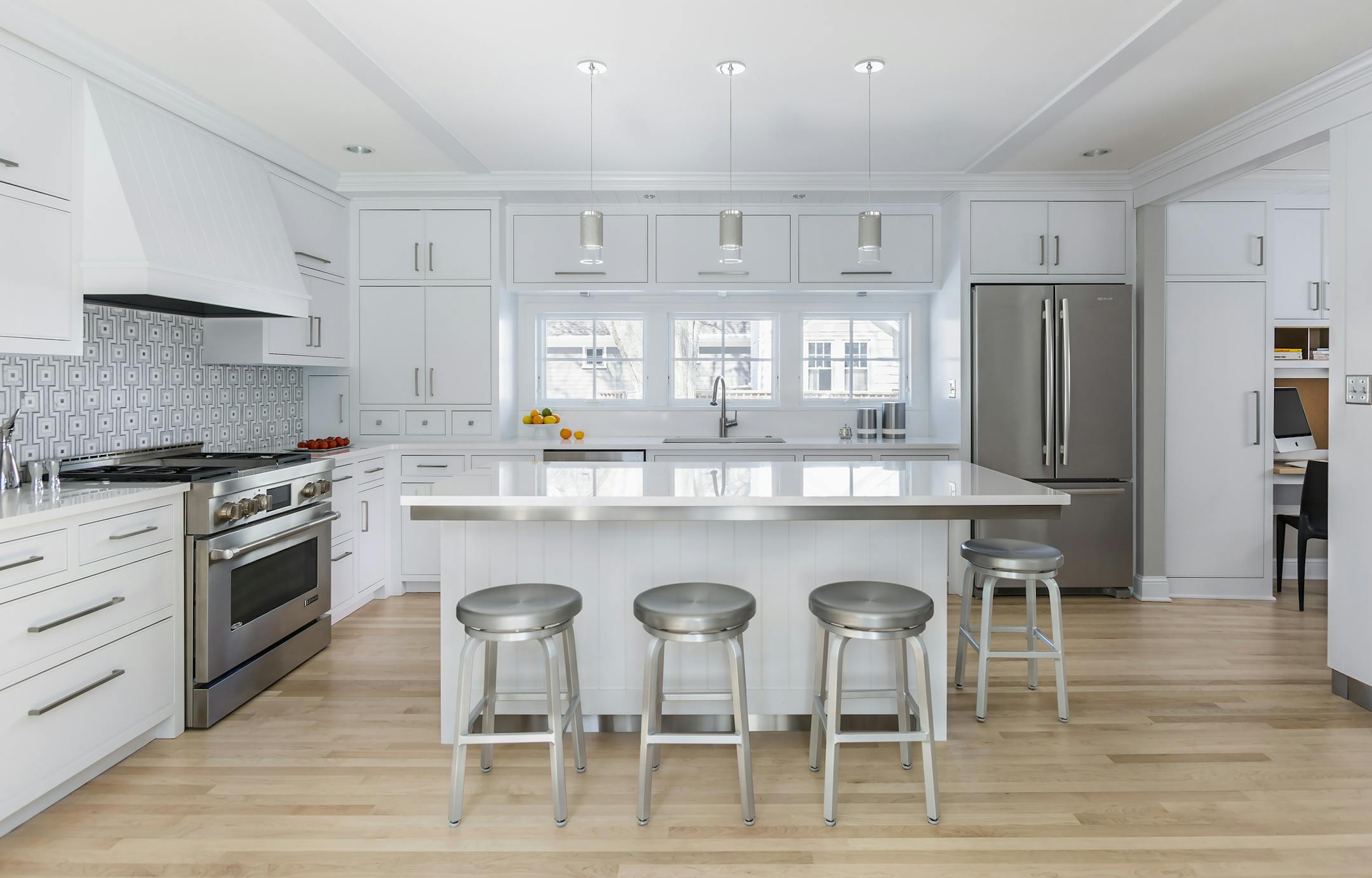 A geometric mosaic backsplash energizes the new white and steel kitchen, which took the spot of the old family room.