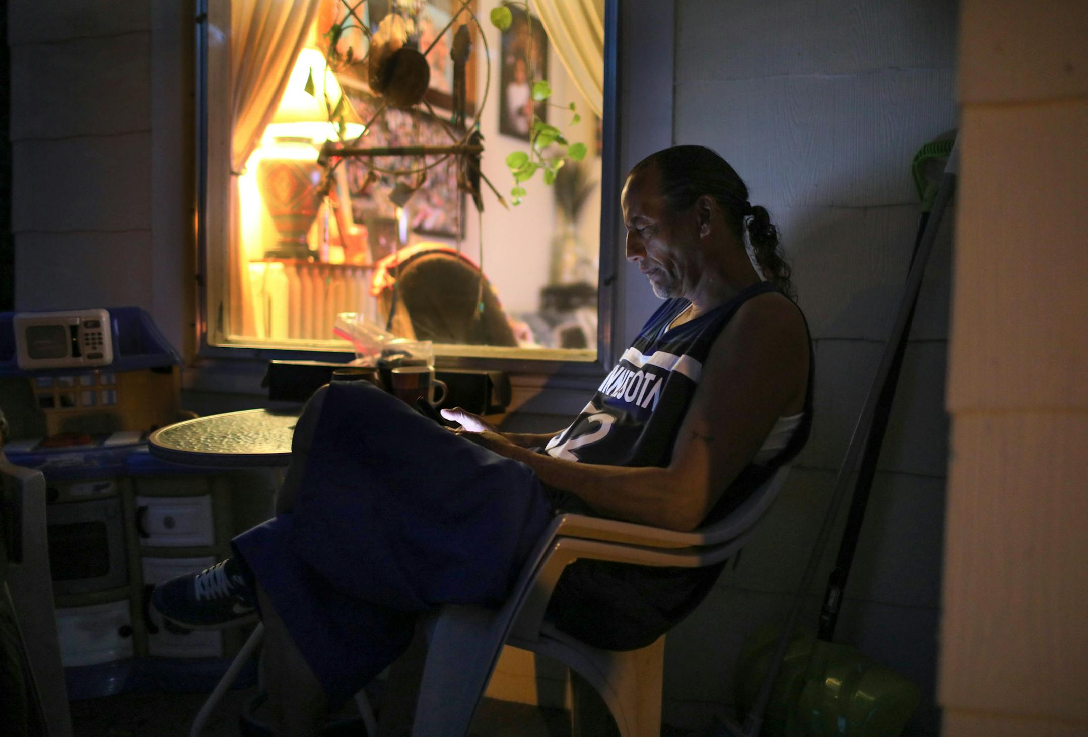 James Cross, the founder of the street outreach group Natives Against Heroin, spent nearly half of his life in prison for drug-related crimes. Here, Cross scrolls through his cell phone while on the porch of his home after a long day at the camp Tuesday, Sept. 11, 2018, in St. Paul, MN. Cross, who has been homeless off and on for much of his life, appreciates having a home but also feels guilty at times and usually fields phone calls from other NAH members while away from the encampment on crisi