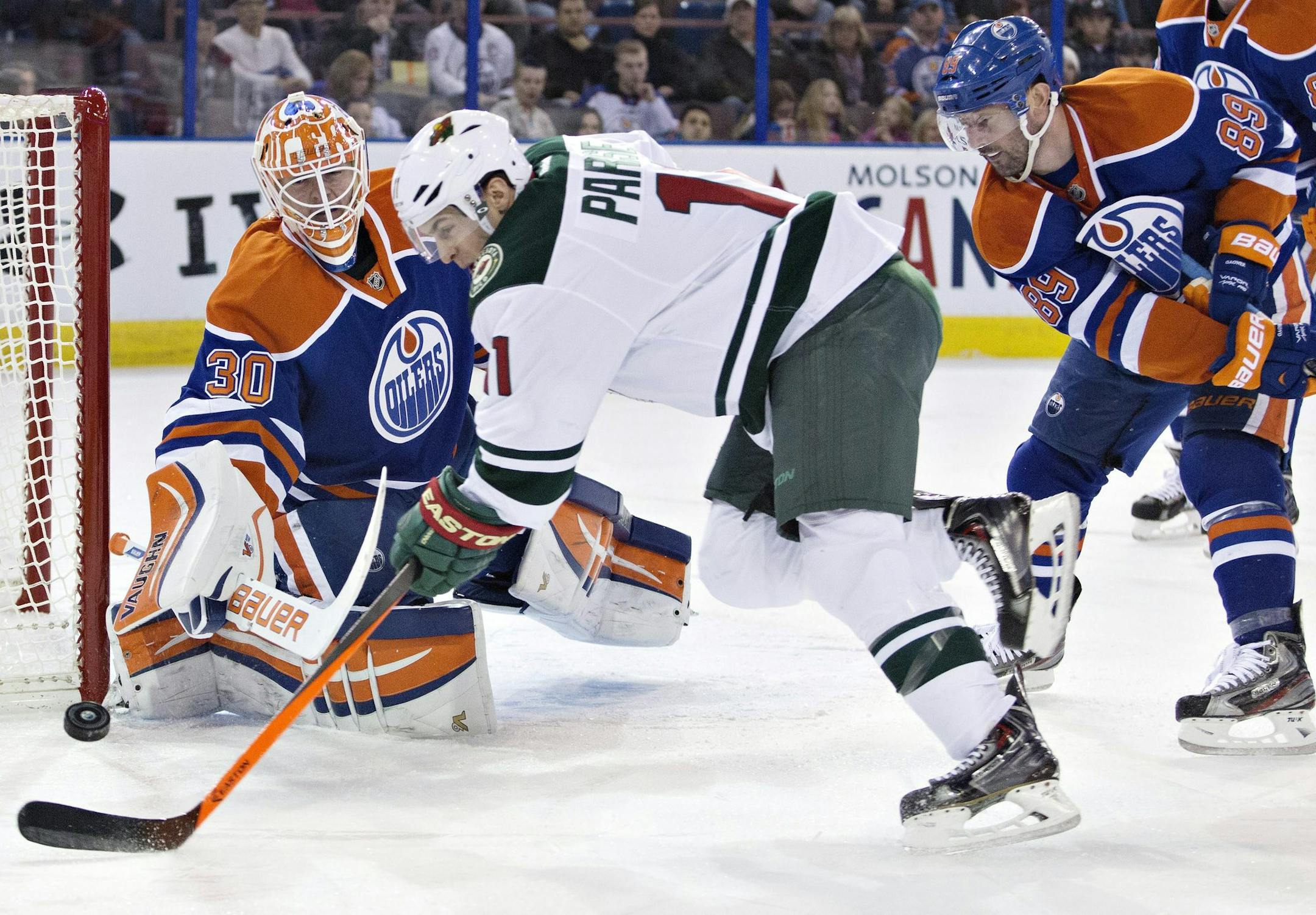 Minnesota Wild's Zach Parise (11) is stopped by Edmonton Oilers goalie Ben Scrivens (30) as Sam Gagner (89) tries to defend during first period NHL hockey action in Edmonton, Canada, Thursday, Feb. 27, 2014. (AP Photo/The Canadian Press, Jason Franson)