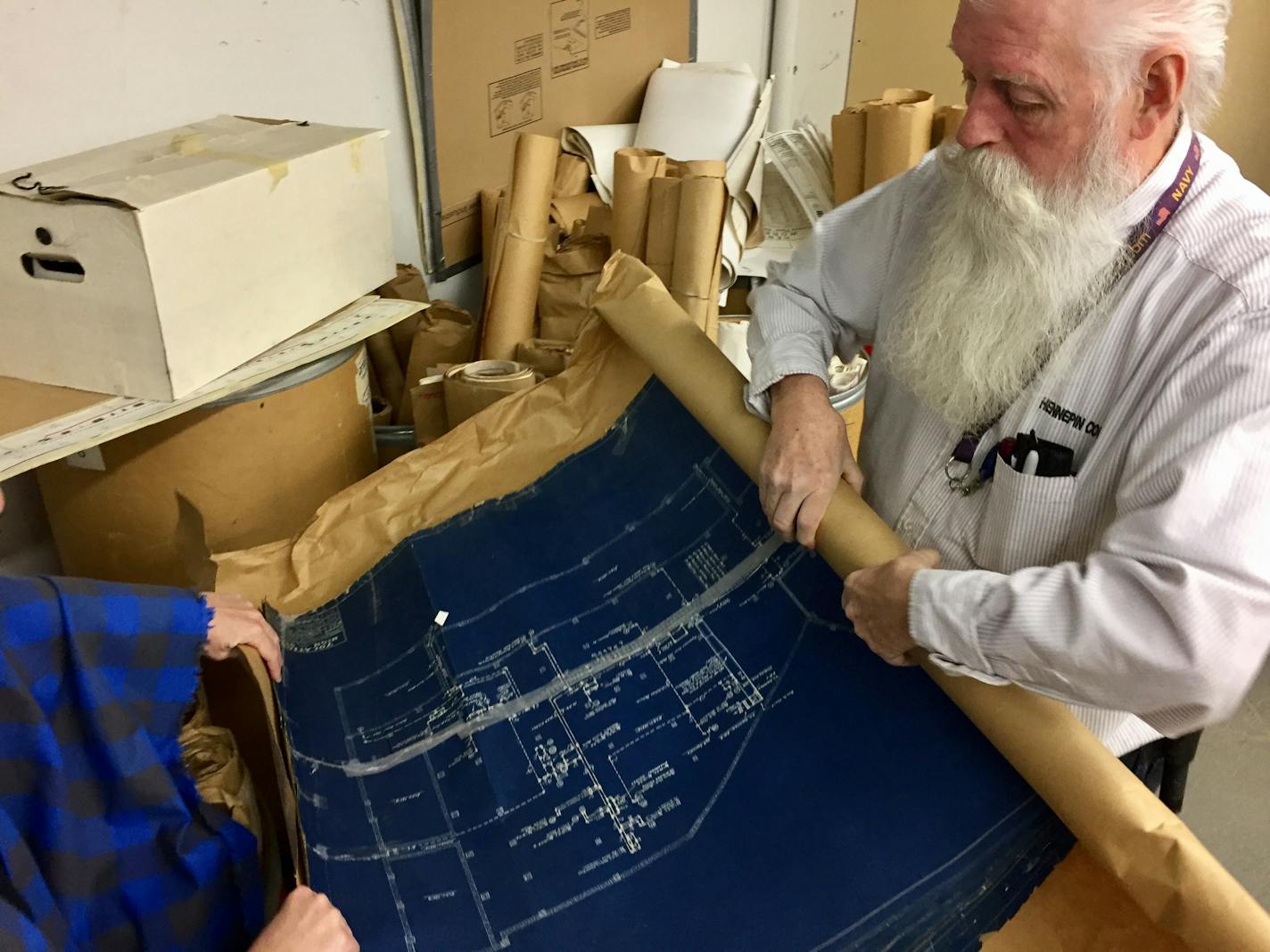 Chris Simmons, a facility maintenance operating engineer for Hennepin County, rolls open a 1931 blueprint of Miller Vocational High School. The 1930s building is now Century Plaza, housing county human services.