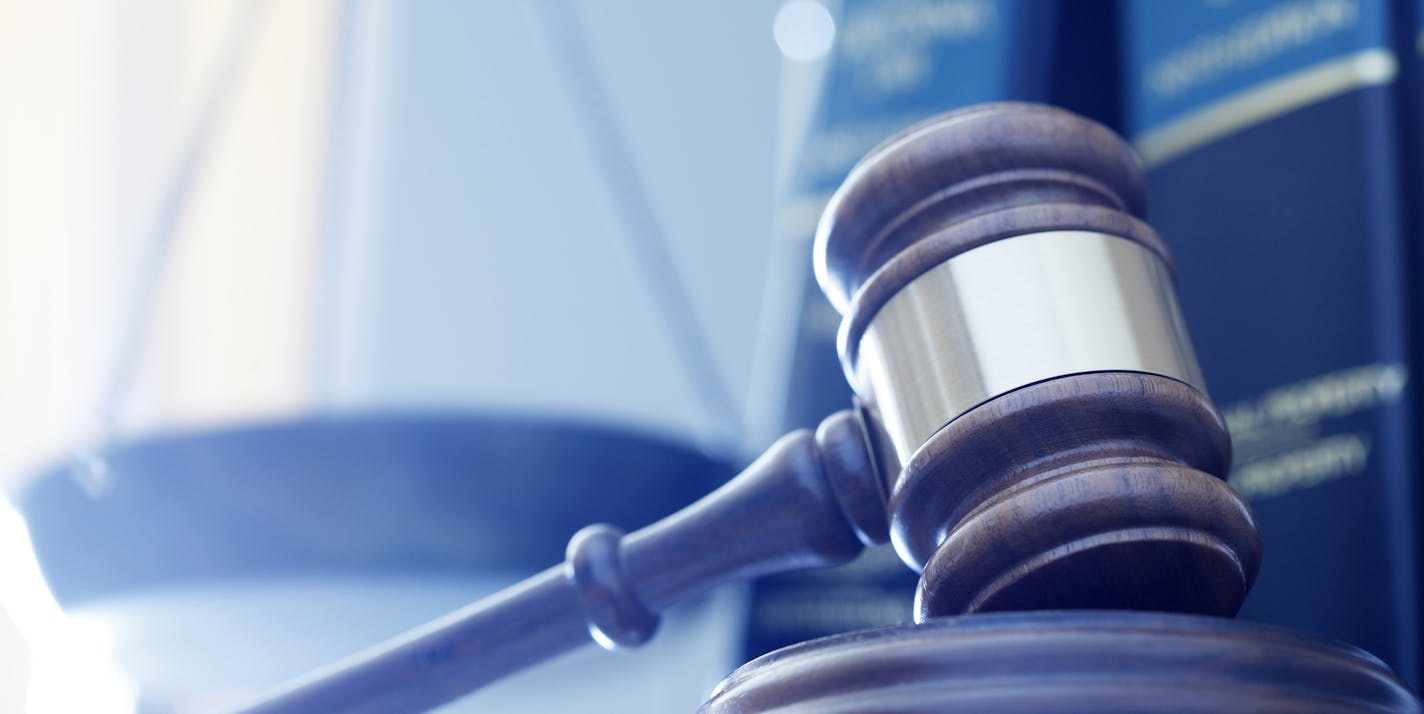 iStock
A gavel rests on its sounding block with a several law books and a justice scale out of focus in the background.