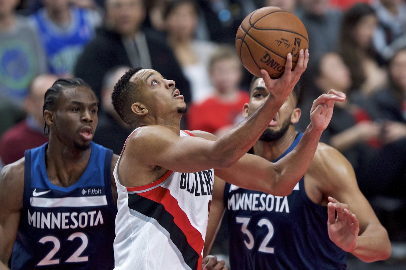 Portland Trail Blazers guard CJ McCollum, center, shoots in front of Minnesota Timberwolves forward Andrew Wiggins, left, and center Karl-Anthony Towns during the second half of an NBA basketball game in Portland, Ore., Wednesday, Jan. 24, 2018. (AP Photo/Craig Mitchelldyer)