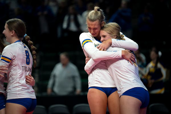 Wayzata High School outside hitter Avery Jesewitz (17) and outside hitter Kate Dimler (15) hug after the team's winning point against New Prague High 