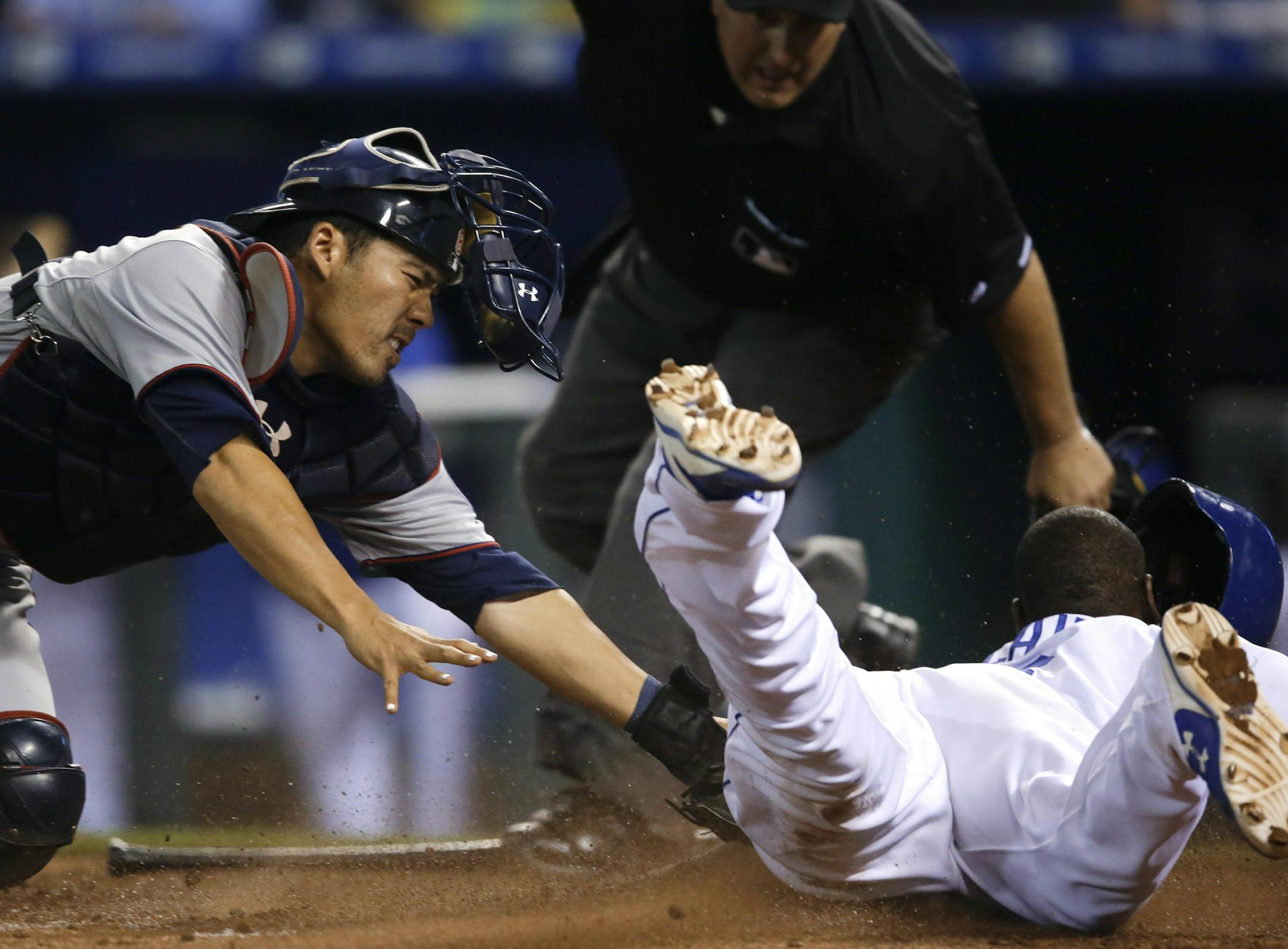 Minnesota Twins catcher Kurt Suzuki, left, misses the tag on Kansas City Royals' Lorenzo Cain, right, during the 10th inning of a baseball game at Kauffman Stadium in Kansas City, Mo., Friday, July 3, 2015. The Royals defeated the Twins 3-2 in 10 innings. (AP Photo/Orlin Wagner)