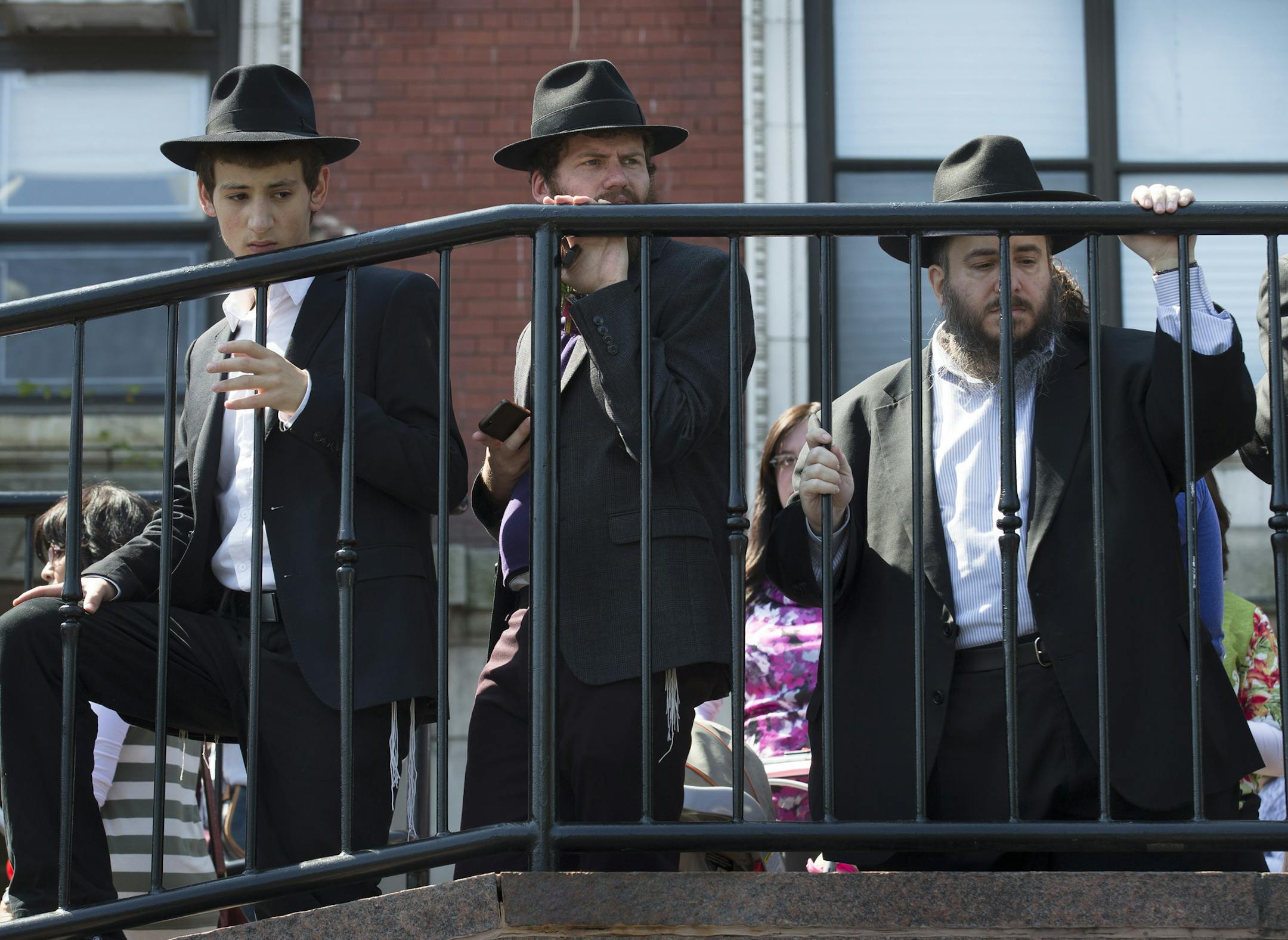Mourners stand by after a hearse carrying the casket of Orthodox Rabbi Joseph Raksin, who was fatally shot Saturday while in Florida visiting relatives, left for burial Monday, Aug. 11, 2014, in the Brooklyn borough of New York. Police have said the death appeared to result from a robbery and not a hate crime, but they're still investigating. (AP Photo/John Minchillo)