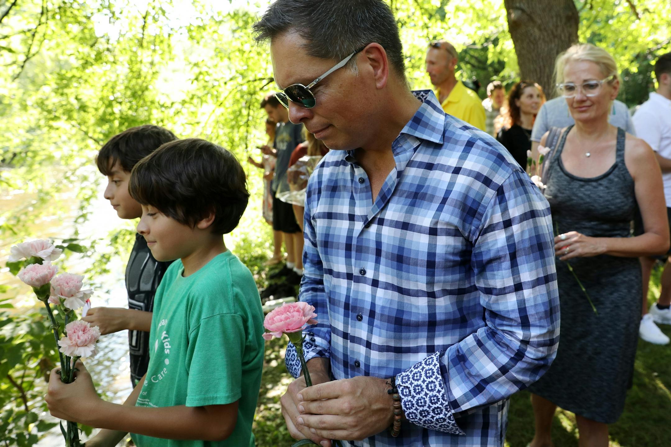 Don Damond looked to throw a flower into the water following a gathering of family and friends to dedicate a bench to Justine Ruszczyk Damond at Minnehaha Creek between 53rd and 54th streets on the one year anniversary of her death.