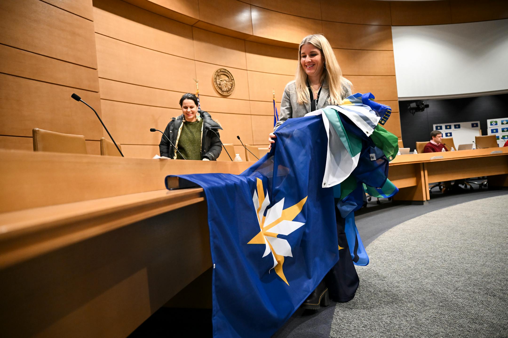 Lindsey Dyer, with the Minnesota Historical Society, folds the six finalist flags after a meeting of the State Emblems Redesign Commission, Tuesday, Dec. 12, 2023 at the Minnesota Senate Building in St. Paul, Minn.. The commission narrowed the decision down to three flags. ] AARON LAVINSKY • aaron.lavinsky@startribune.com